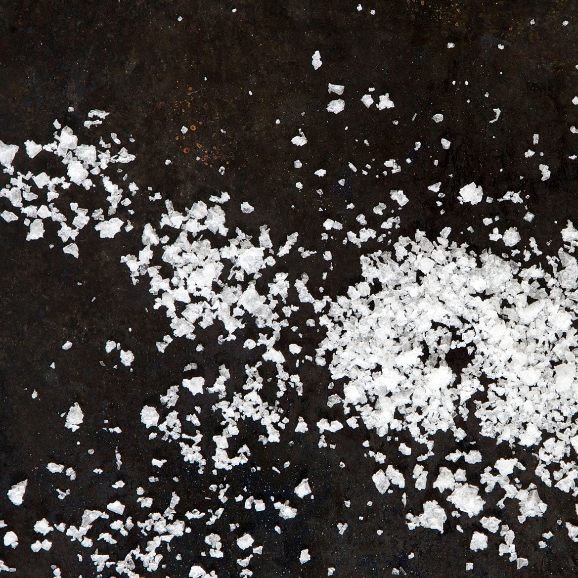 Icelandic flaky sea salt scattered on a surface, demonstrating the crunchiness and mineral richness of Saltverk's artisanal salt
