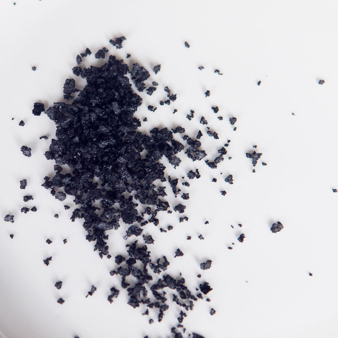 Icelandic lava salt scattered on a surface, showcasing the striking black color and rich mineral content of Saltverk's volcanic sea salt